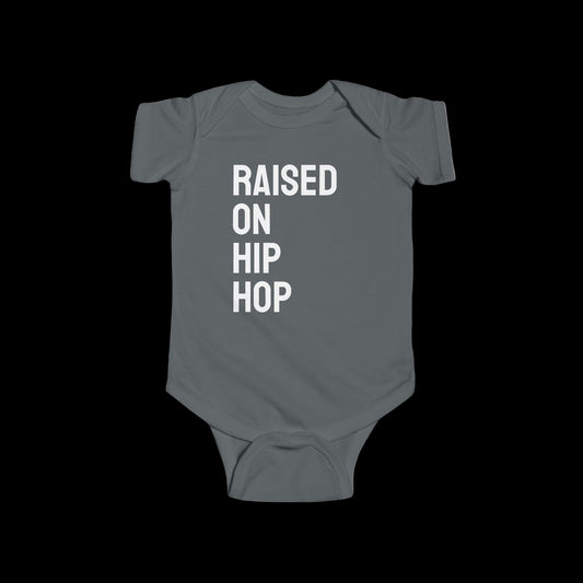 Gray baby onesie with 'Raised on Hip Hop' text on a white background